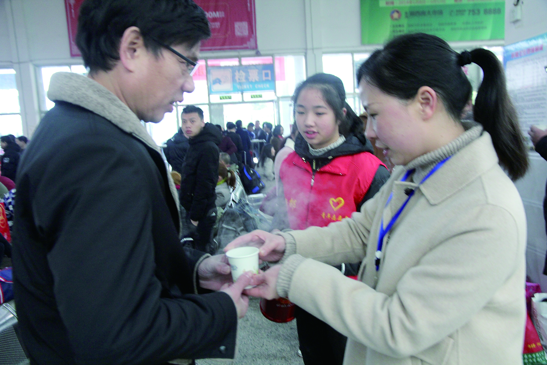 母女服務(wù)春運(yùn) 2月13日，記者在新邵分公司汽車站看到，該分公司安全科副科長李喜梅與其在新邵一中初中部1701班就讀女兒劉嘉怡在車站擔(dān)當(dāng)志愿者。李喜梅在候車室耐心為旅客釋疑解惑，劉嘉怡為旅客遞上一杯杯熱茶，有時母女也相互合作，其樂融融。 祖冠 攝影報道